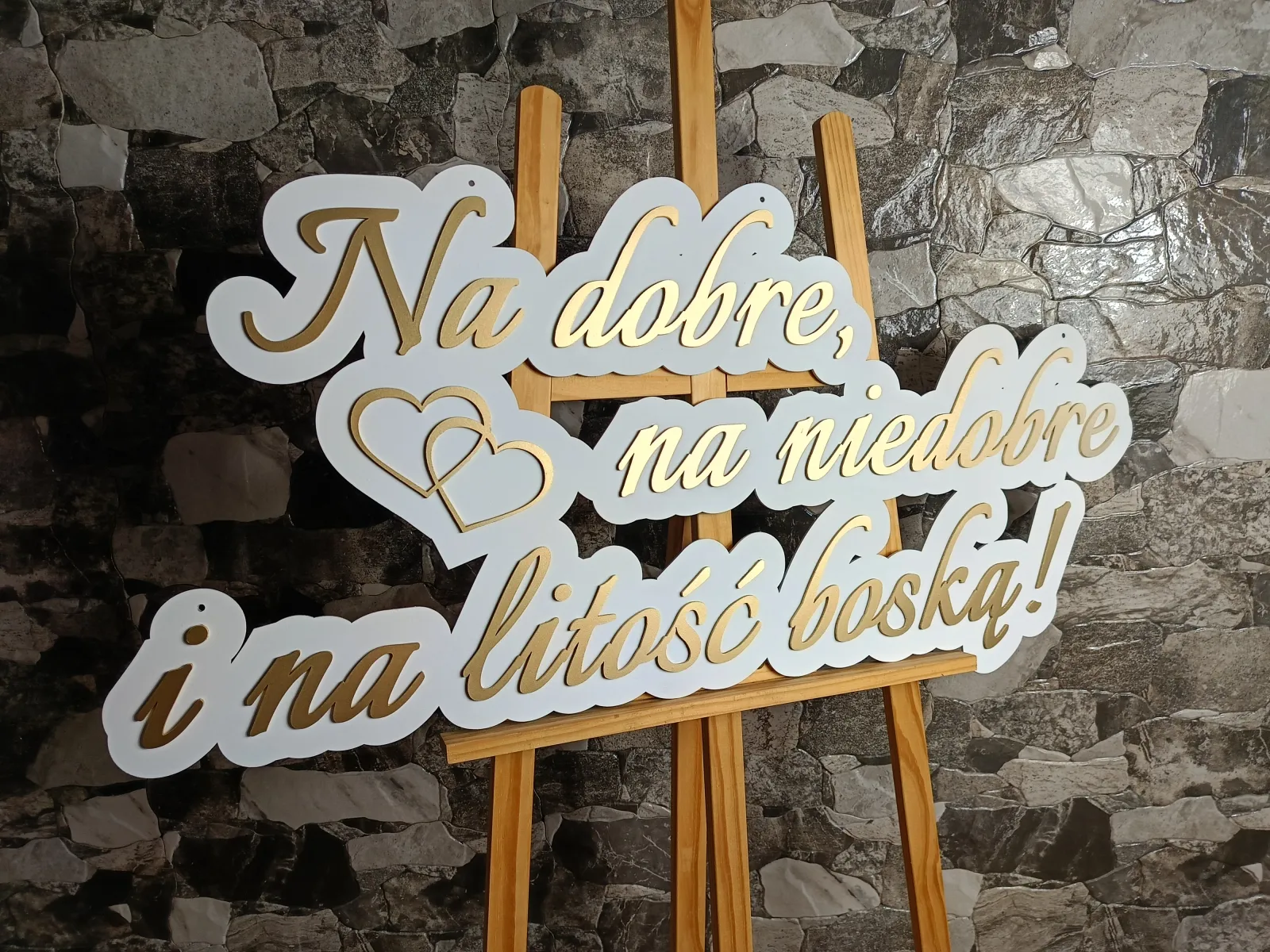 Elegancki napis dekoracyjny w stylu glamour w kolorach bieli i złota to idealne dopełnienie ślubnej ścianki. Subtelny blask złotych detali w połączeniu z klasyczną bielą tworzy wyjątkowo luksusowy efekt, który przyciąga wzrok i pięknie prezentuje się na zdjęciach. To stylowy akcent, który doda Waszej uroczystości wyjątkowej klasy i romantycznego klimatu.